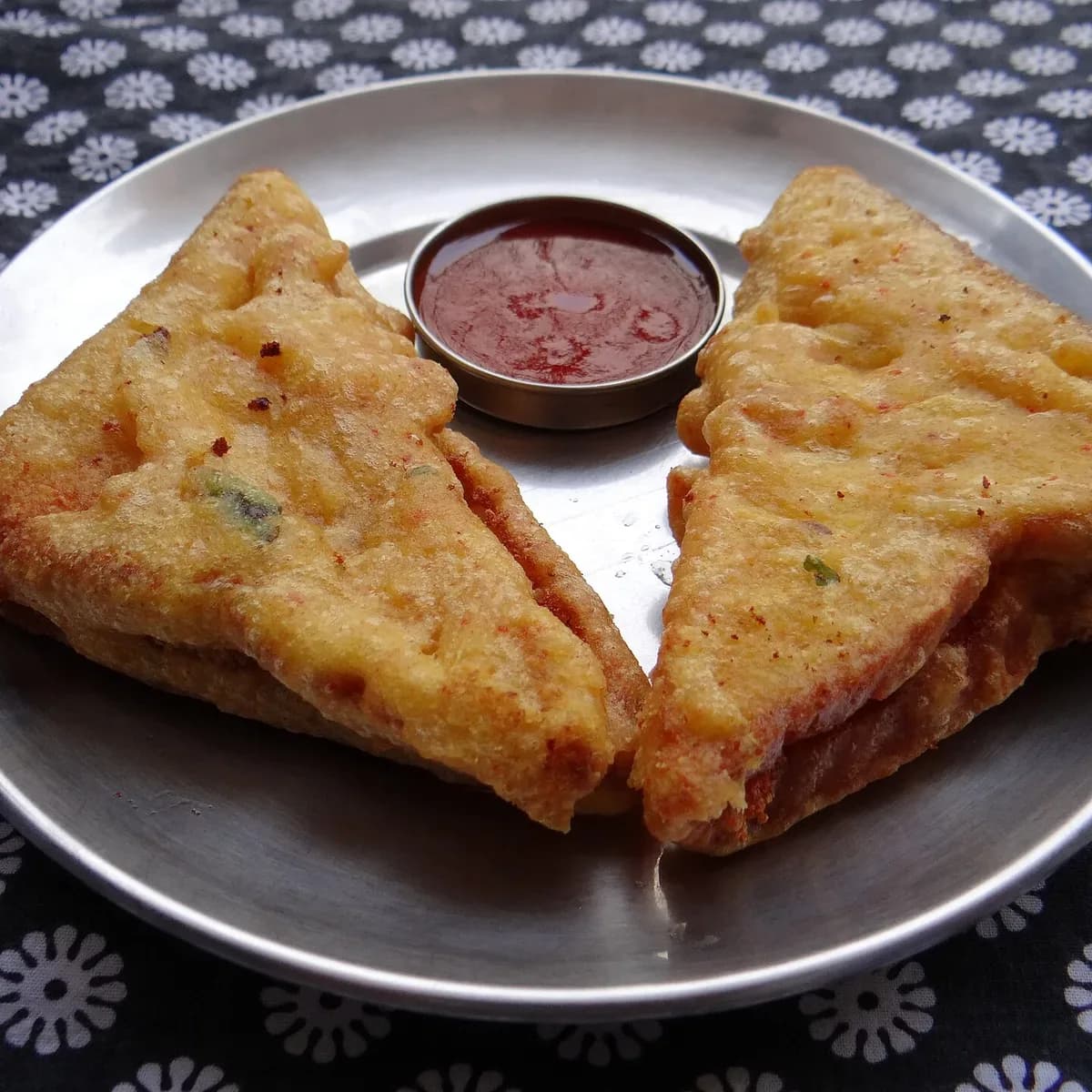 Golden bread pakoras stuffed with spiced potato, with red chutney