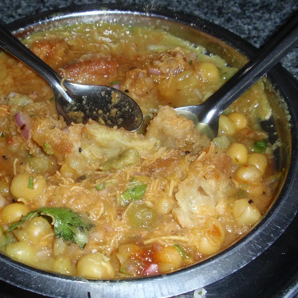 Samosa topped with spiced chhole, onion and sev