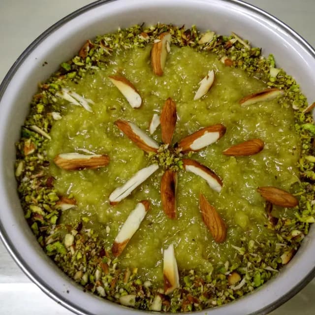 Green ghiya (lauki) sweet set in a pan, topped with almonds and pistachio