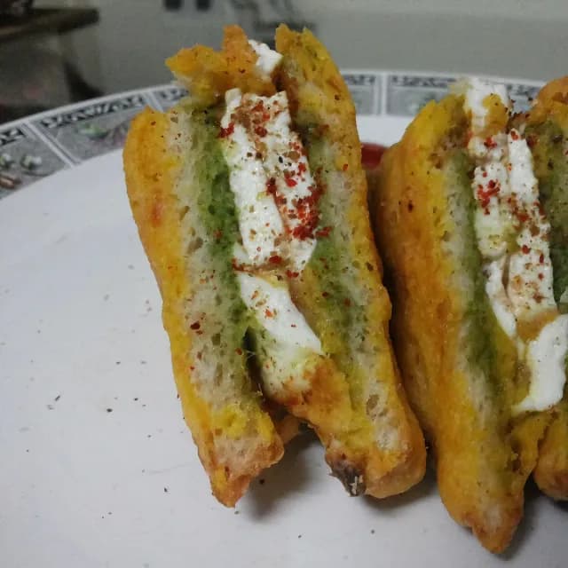 Paneer bread pakora cut open to show the paneer and green chutney layers