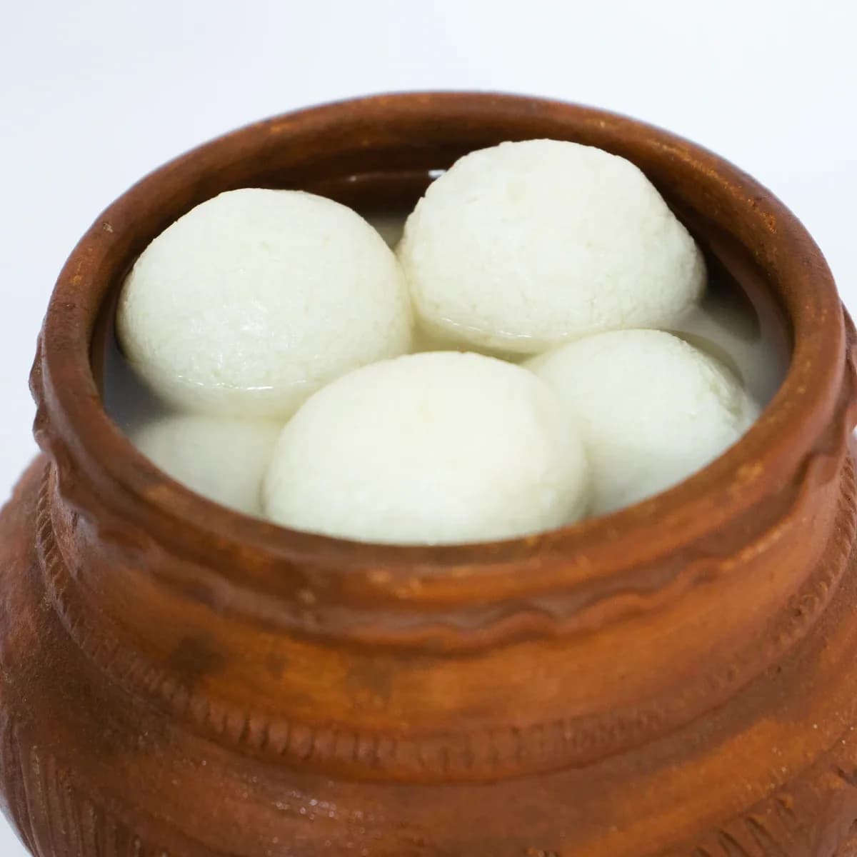 Soft white rasgullas in a clay pot