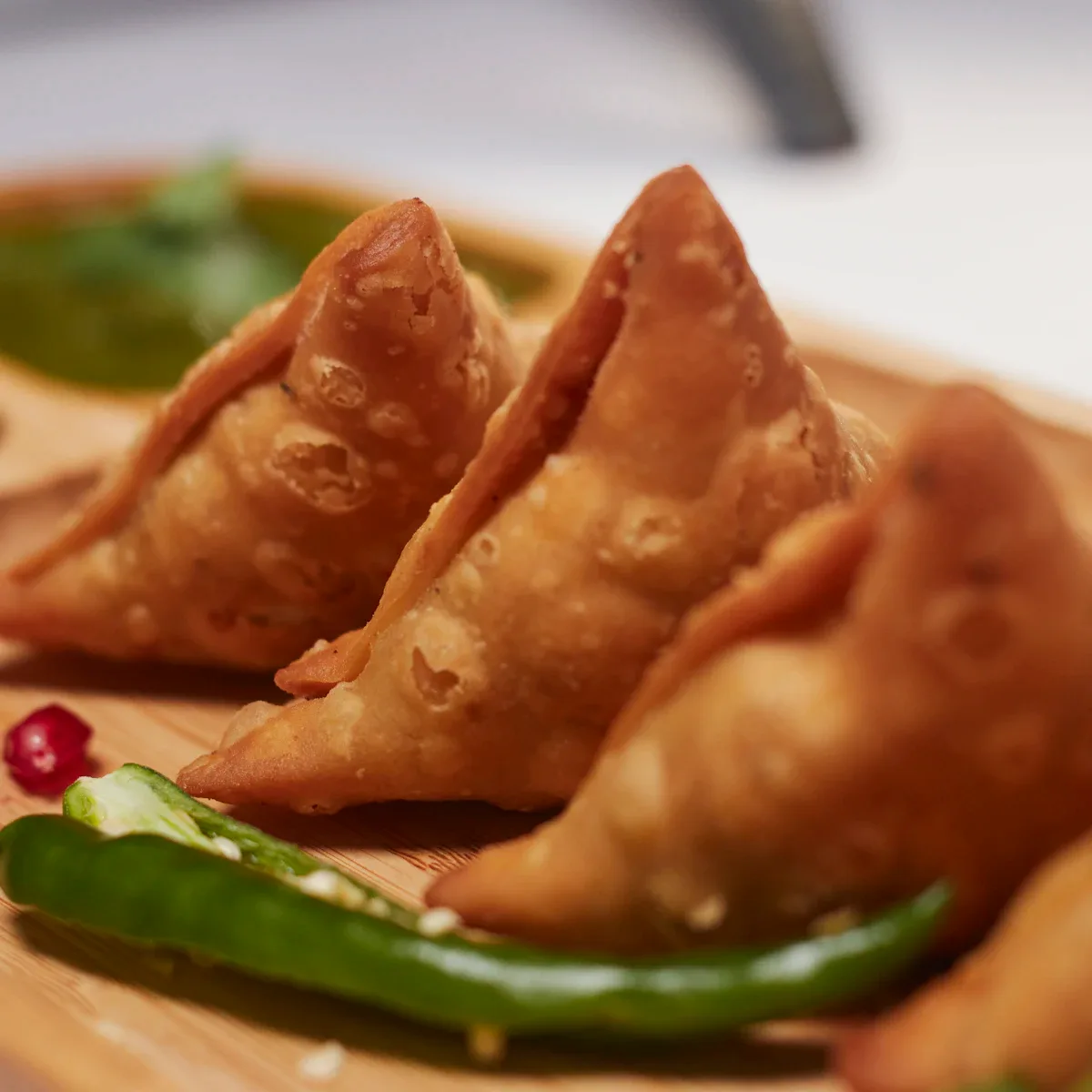 Golden fried samosas with a green chilli