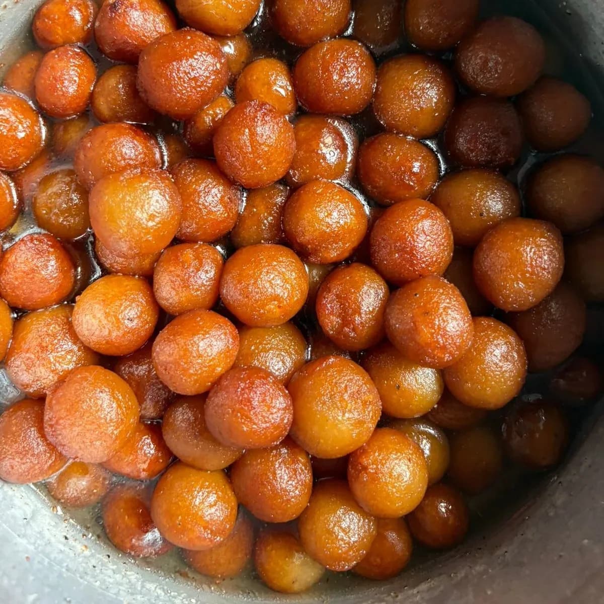 चाशनी में भरे छोटे सुनहरे गुलाब जामुन