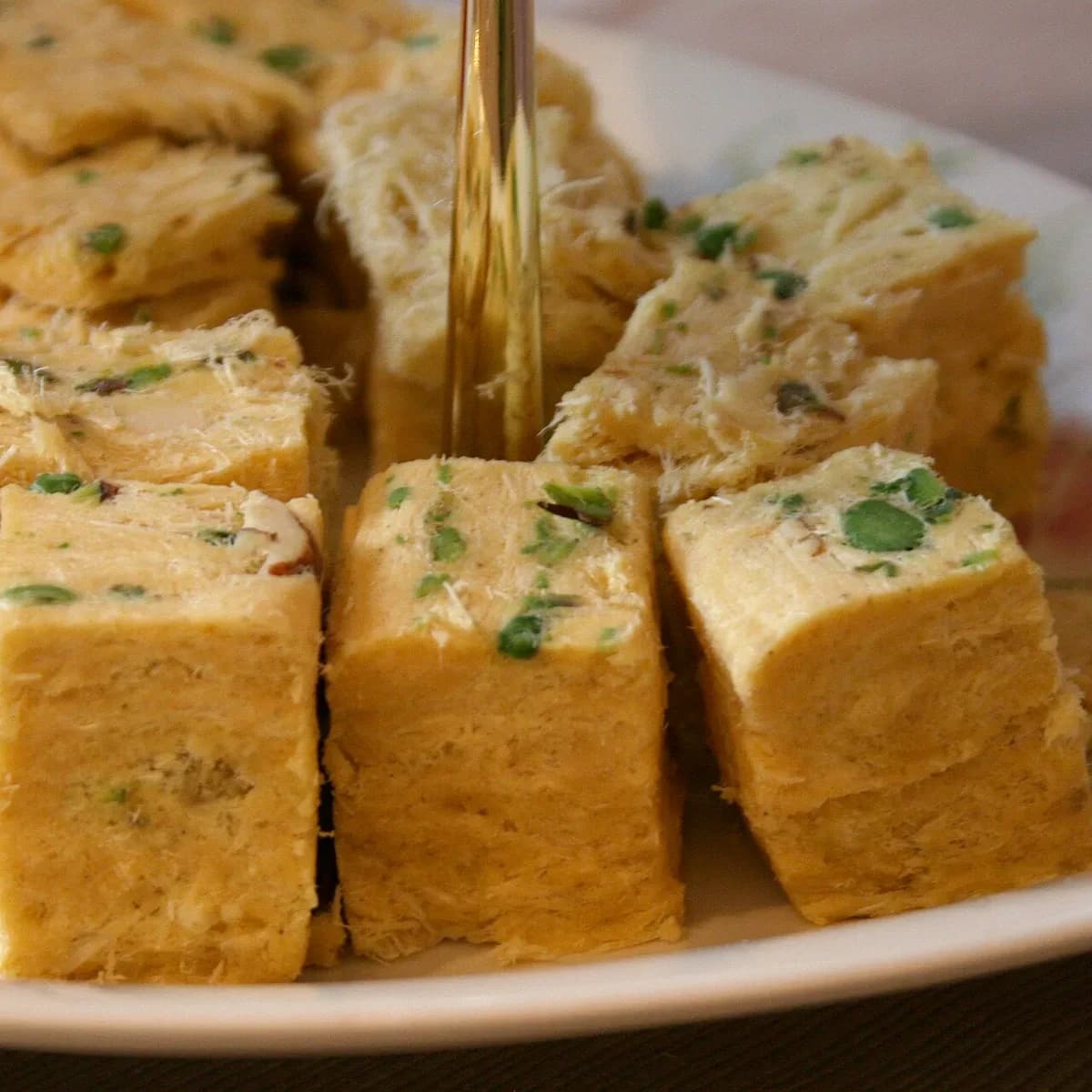 Flaky cubes of patisa sprinkled with pistachio